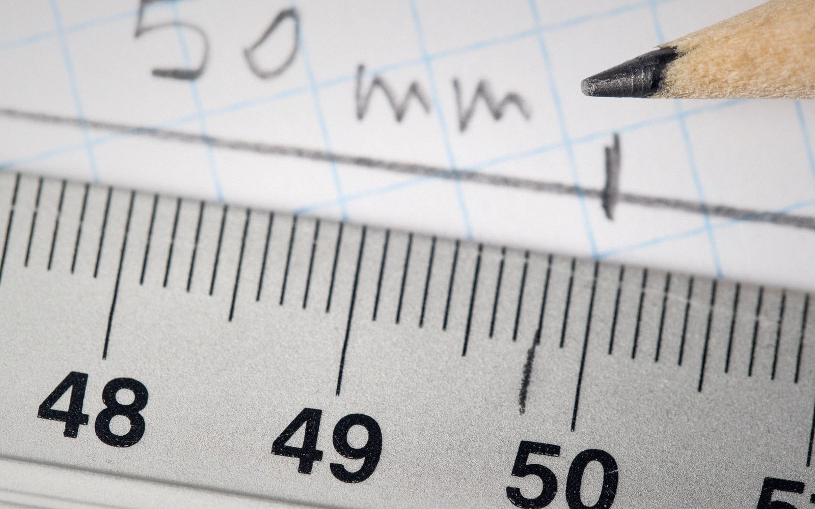 A metal ruler measures a pencil-drawn line labeled 50mm on graph paper