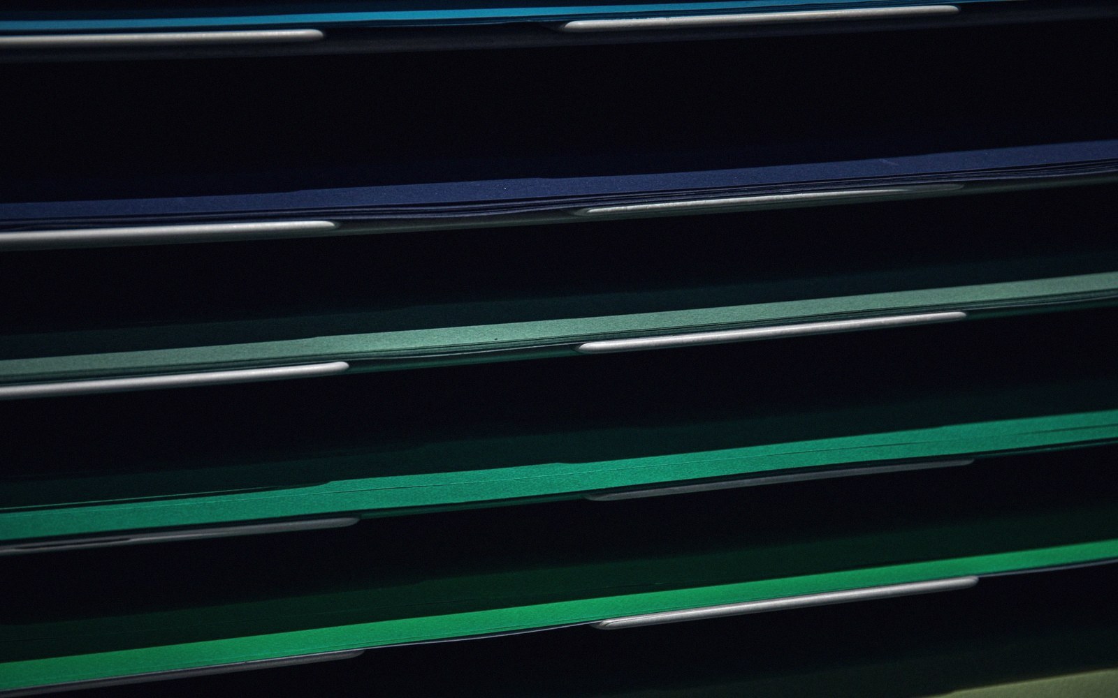 Stacked layers of blue and green folders shot in dim, moody lighting