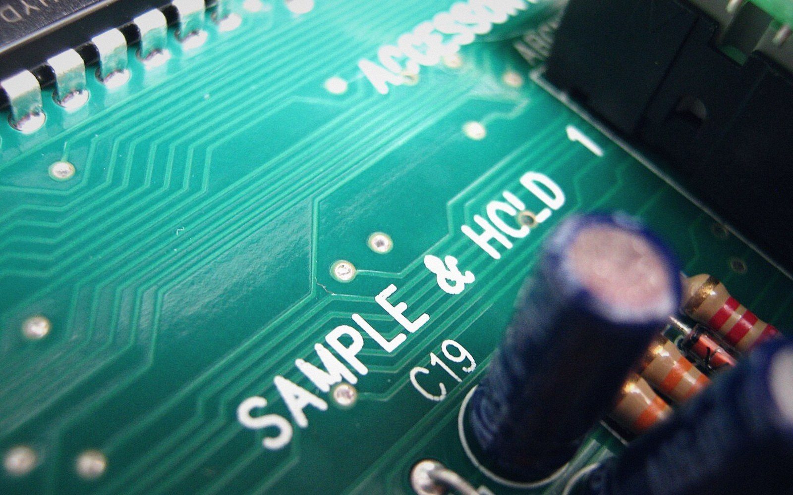Close-up of a green circuit board labeled "sample & hold" near capacitors and a microchip