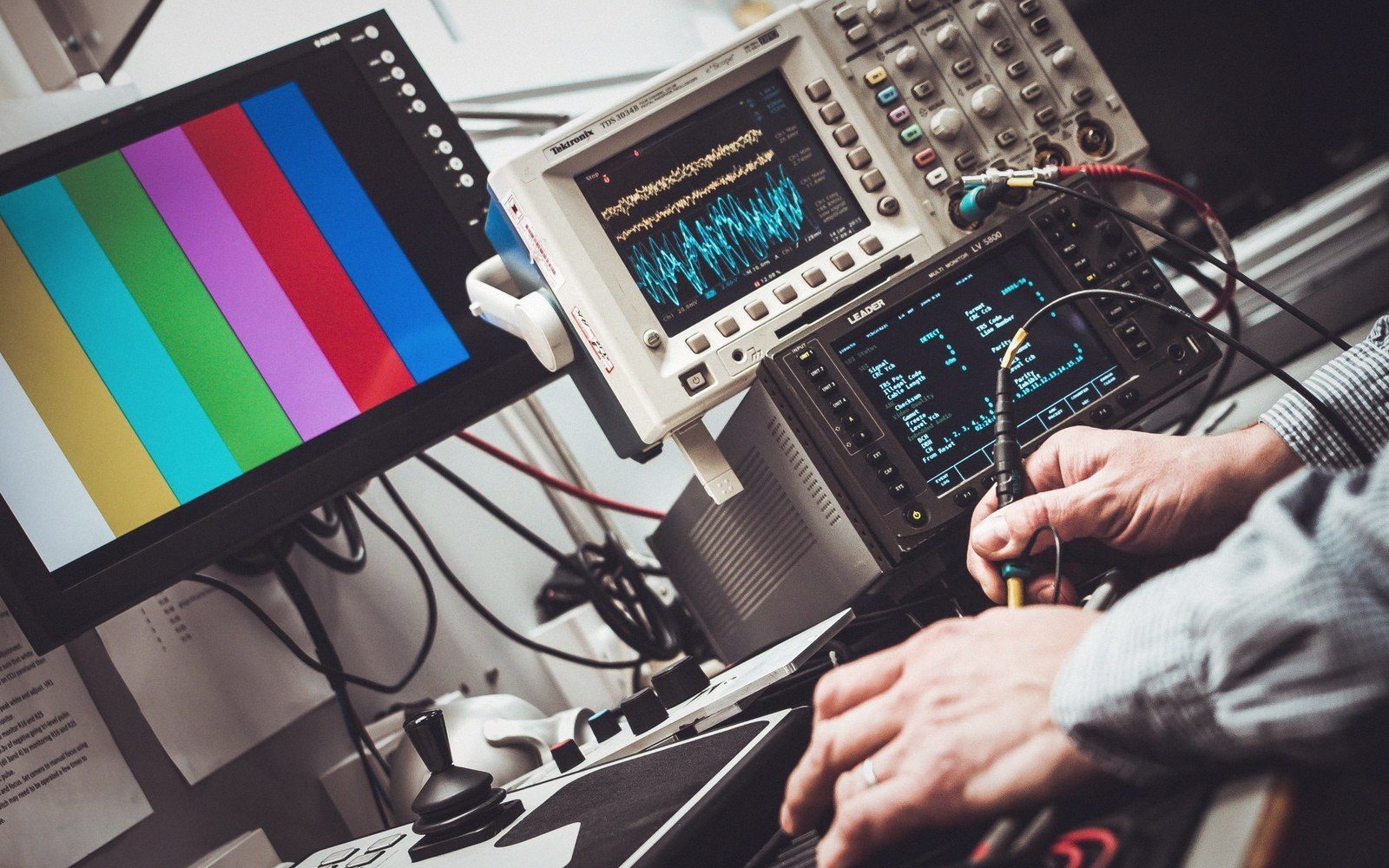 Oscilloscope screen showing a sync-pulse waveform with sharp vertical edges, instrument bezels visible in the foreground